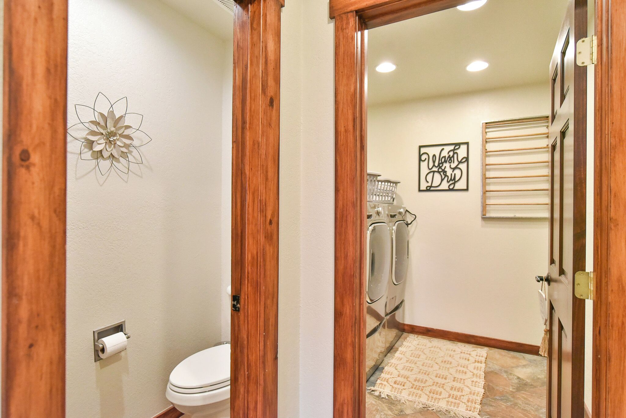 Une salle de bain avec des toilettes, un cadre de porte en bois, un porte-serviettes fixé au mur et une pancarte indiquant « Laver et sécher ».