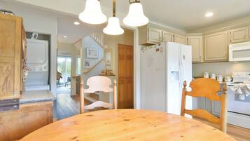 A kitchen with wooden cabinets, a white refrigerator, and a wooden dining table.