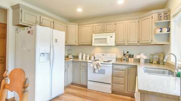 A kitchen with light-colored cabinets, a refrigerator, a microwave, an oven, and a sink.