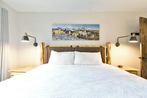 A bed with white bedding, a wooden headboard, and two bedside tables with lamps. - Pine Ridge Off-Piste Condo - Ski In, Walk to Downtown! (Breckenridge)