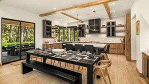 Una cocina moderna con armarios de madera, una isla central y un comedor con una mesa grande para seis personas.