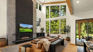 Una sala de estar moderna con chimenea, ventanas amplias y una zona de estar acogedora.
