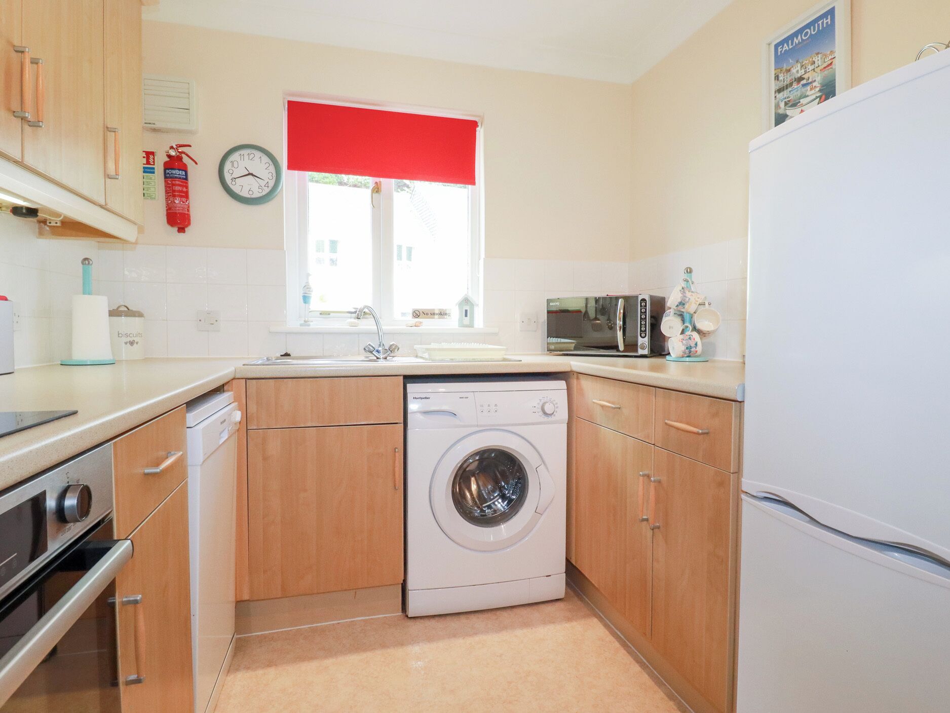A compact kitchen with a washing machine, a microwave, and a refrigerator.