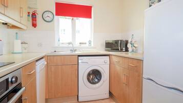 A compact kitchen with a washing machine, a microwave, and a refrigerator.