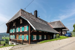 A traditional chalet with a steeply pitched roof, wooden exterior, and multiple windows with shutters. - Kaiserberg Apartment with Garden BBQ Hut and Views of the Beautiful Bernau Valley (Bernau im Schwarzwald)