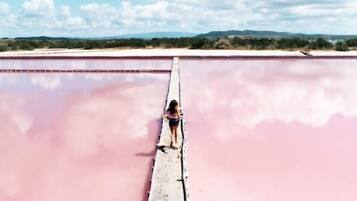 Una persona de pie sobre un puente estrecho sobre una gran extensión de agua, con un paisaje al fondo.