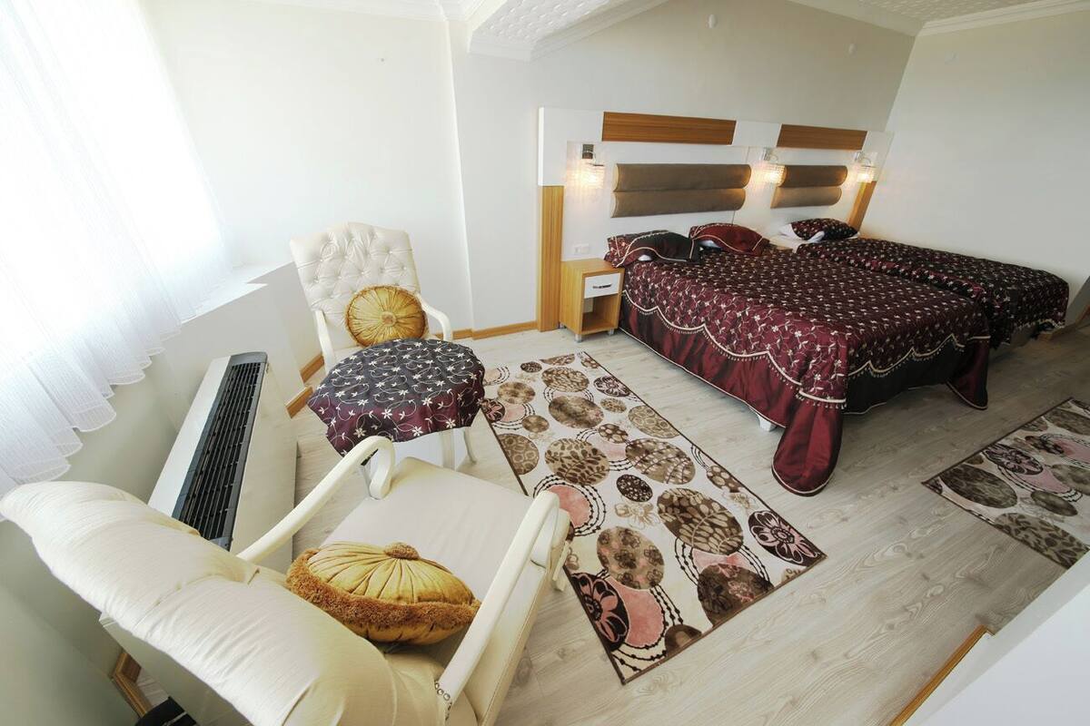 Quarto com cama, cadeira, mesa de cabeceira e uma janela grande.
