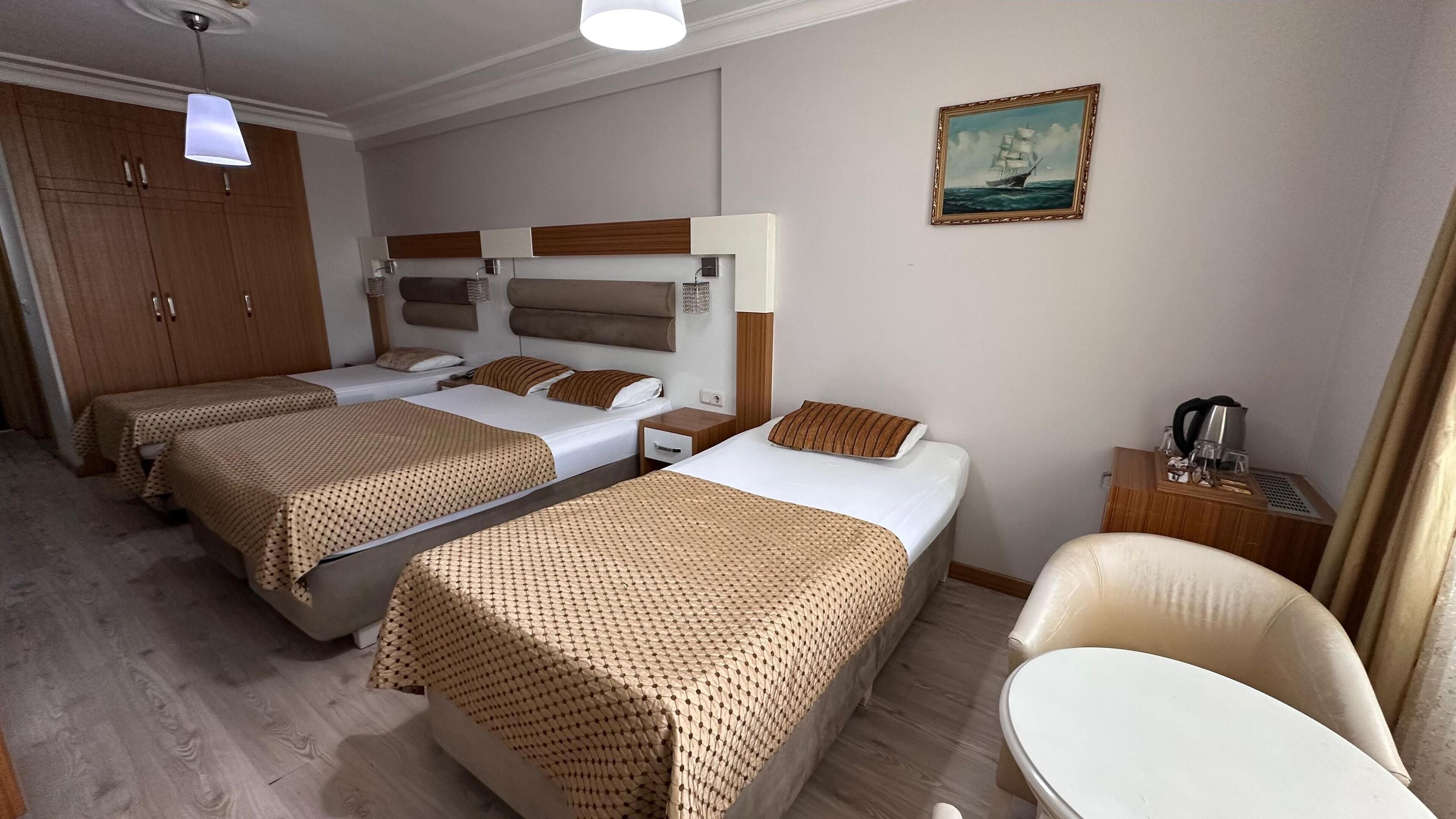 Et hotelværelse med to senge, en sofa, et lille bord og et billede på væggen.