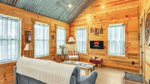 Un chalet confortable avec des murs en bois, un canapé, une table et une cheminée.