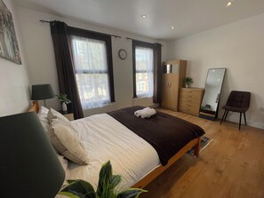 A bedroom with a bed, a wardrobe, a mirror, and a chair.
