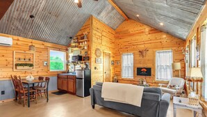 A cozy log cabin interior with a dining area, kitchen, and living room.