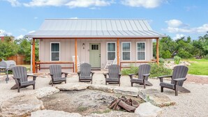 A two-story building with a metal roof and a front porch with Adirondack chairs.