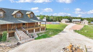 A log cabin with a porch and a tennis court.