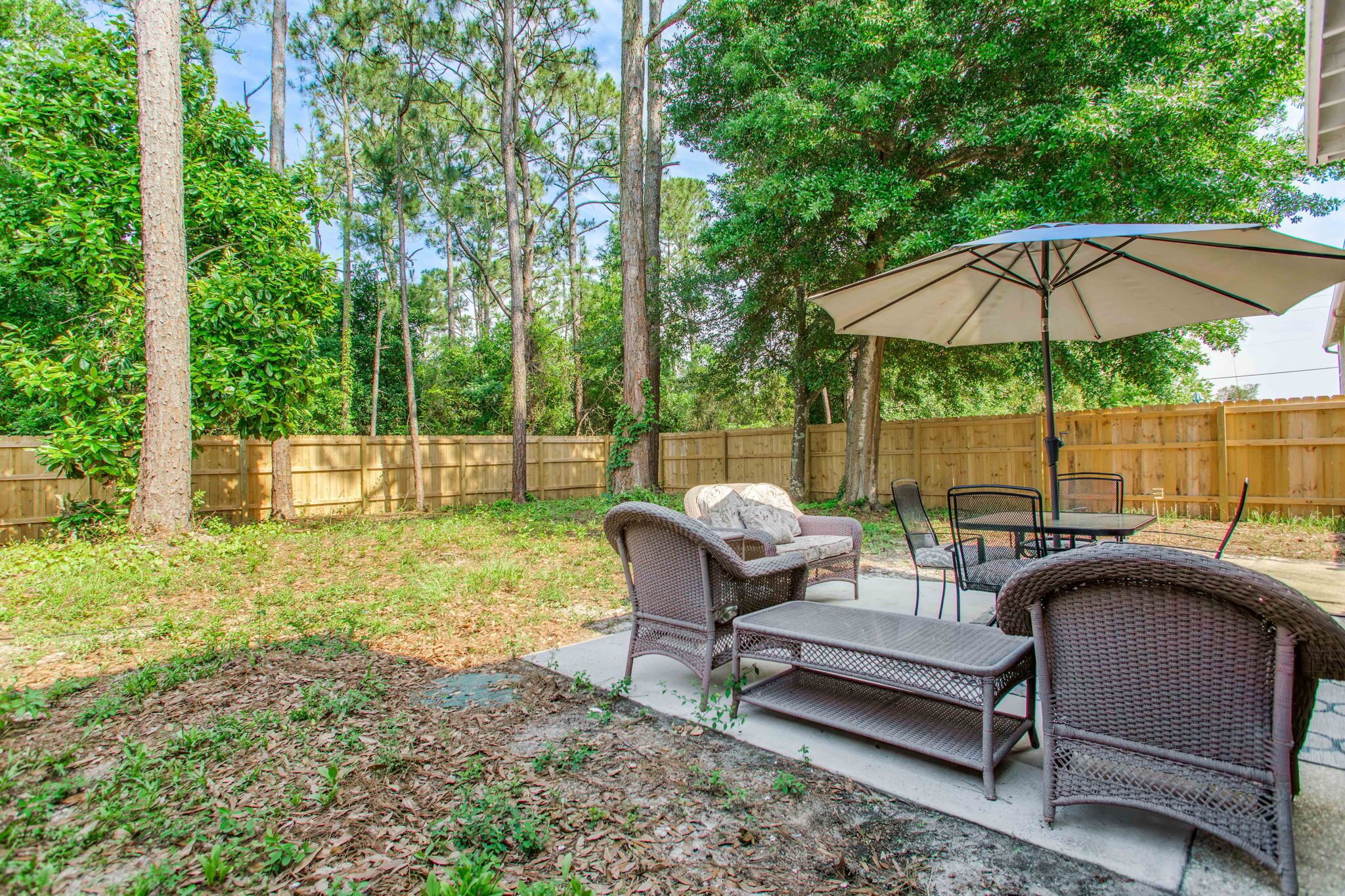 Une terrasse extérieure aménagée avec des meubles en osier, une table et un parasol.