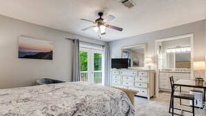 Ein Schlafzimmer mit Bett, Deckenventilator, Kommode, Schreibtisch und Stuhl.