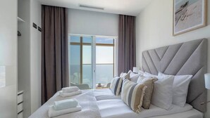A hotel room with a large bed, a bedside table, a lamp, and a window with curtains. - Intempo Spa (Benidorm)