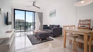 A modern living room with a sofa, ottoman, dining table, chairs, and a ceiling fan. - Cassia Residences, Two-Bedroom C Deluxe Lake (Choeng Thale)