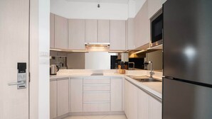 A modern kitchen with light wood cabinets, stainless steel appliances, and a built-in microwave. - Cassia Residences, Two-Bedroom C Deluxe Lake (Choeng Thale)