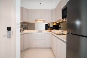 Une cuisine moderne avec des meubles en bois clair, des appareils en acier inoxydable et un four à micro-ondes encastré.