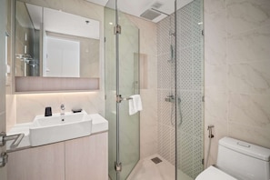 Une salle de bain moderne avec une douche à parois de verre, un lavabo blanc et des toilettes.