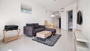A modern living room with a sofa, coffee table, and a luggage rack. - Cassia Residences, Two-Bedroom C Deluxe Lake (Choeng Thale)