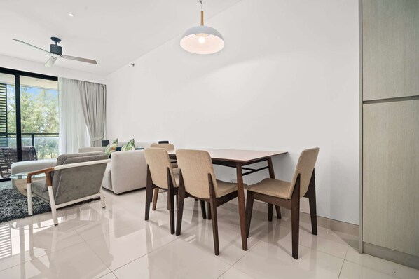 A modern dining area with a table and chairs, a ceiling fan, and a large window with curtains.