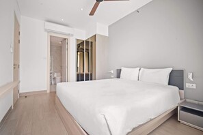 Une chambre à coucher moderne avec un grand lit, un ventilateur de plafond et un dressing.