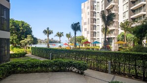 A modern hotel with a pool area, surrounded by lush greenery and palm trees. - Cassia Residences, One Bedroom A Ground Floor (Choeng Thale)