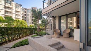 A modern apartment building with a balcony, outdoor seating, and a well-maintained garden. - Cassia Residences, One Bedroom A Ground Floor (Choeng Thale)