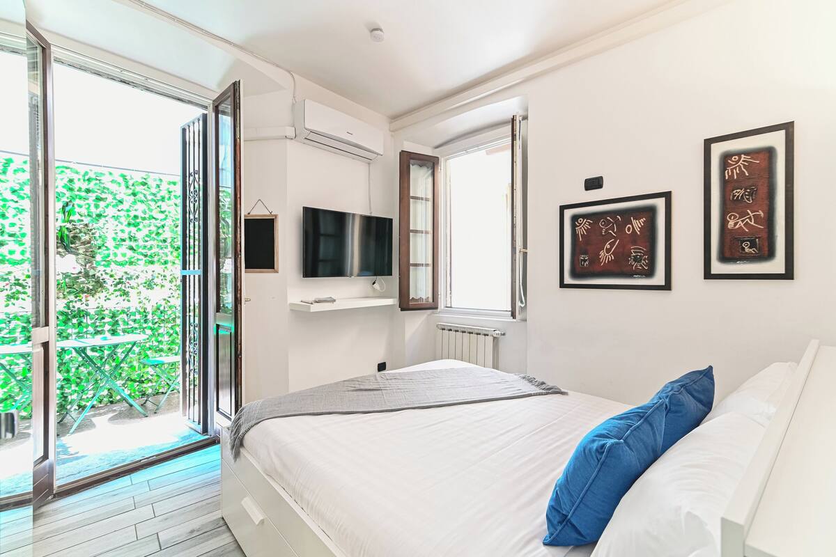 A bedroom with a bed, a TV, and artwork on the wall.