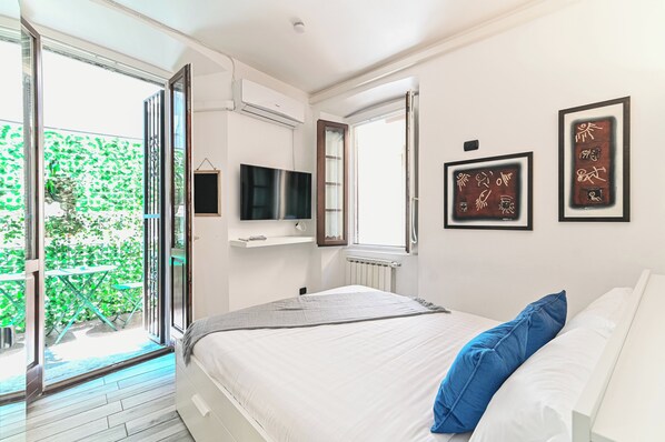 Un dormitorio con cama, televisor y obras de arte en la pared.