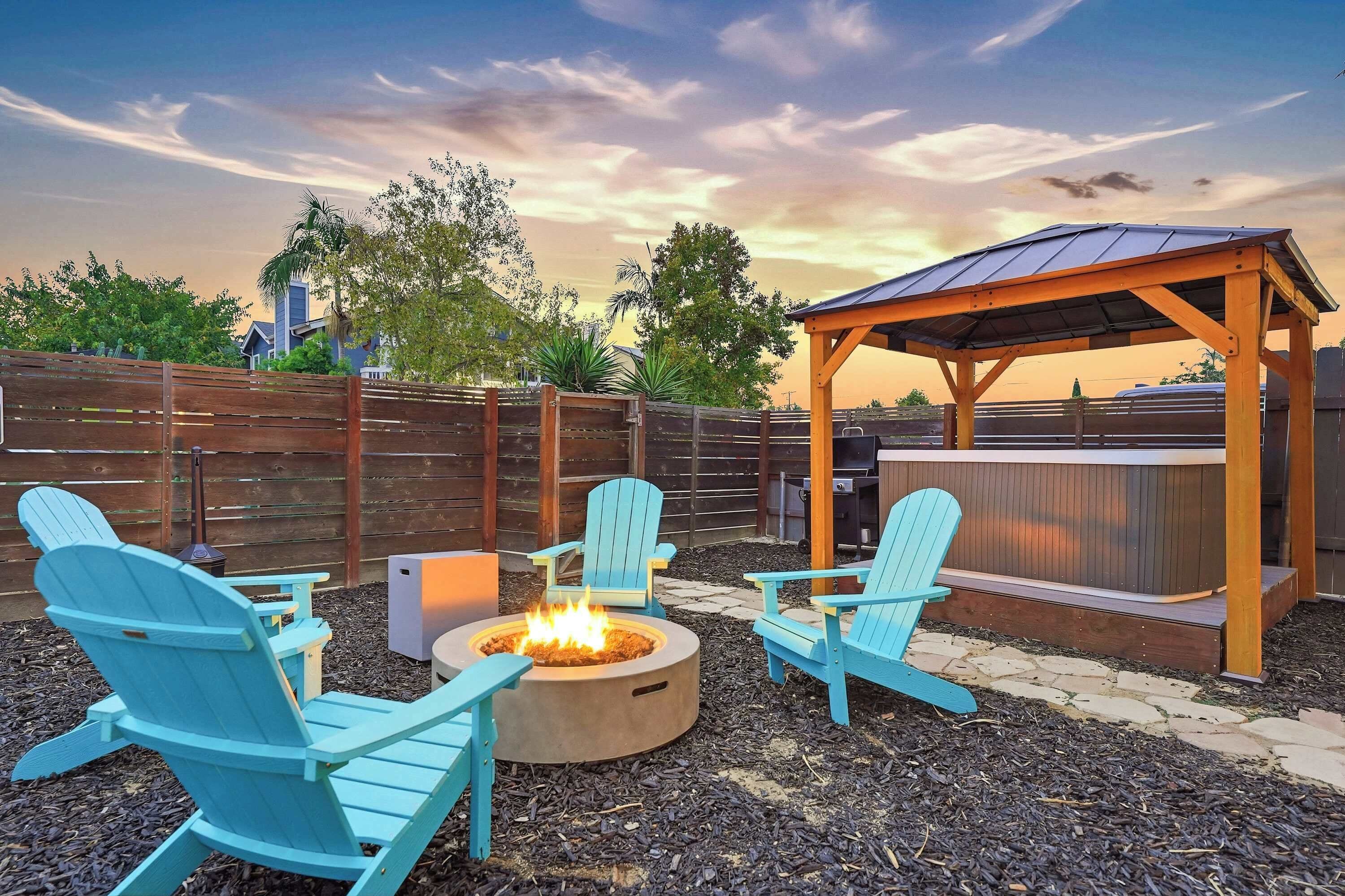 An outdoor seating area with a fire pit and Adirondack chairs.