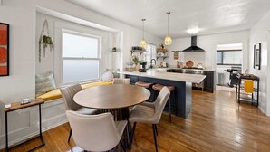 A modern kitchen with a central island, wooden flooring, and pendant lighting.