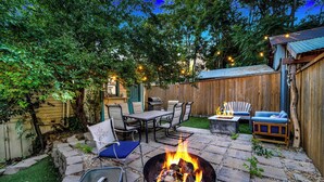 Un jardin avec un foyer extérieur, du mobilier de jardin et une clôture en bois.
