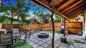 Un patio trasero con una fogata, mobiliario exterior y una terraza de madera.
