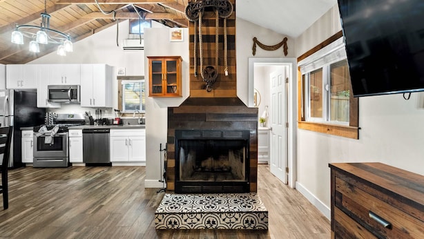 Una cocina moderna con chimenea, vigas de madera y un televisor grande.