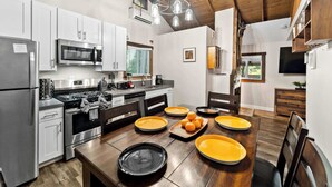 Una cocina moderna con electrodomésticos de acero inoxidable, una mesa de comedor de madera con platos y una araña.