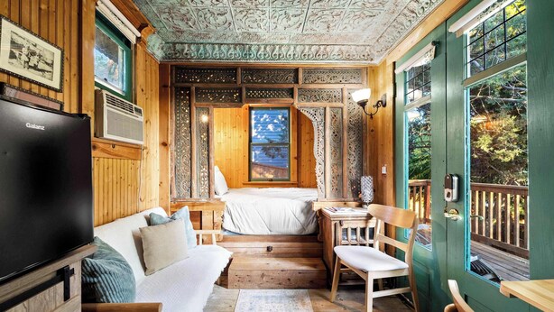 A wooden cabin with a bed, a TV, and a dining area. - Escape to Rustic Studio | Fireplace + Modern Comfort (Julian)