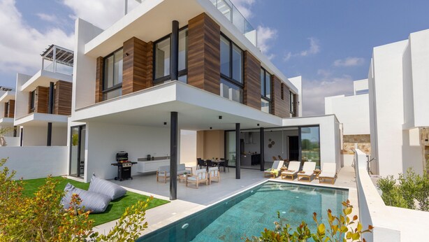 Una casa moderna a due piani con terrazza sul tetto, piscina e patio arredato.