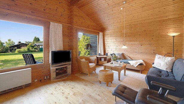 A wooden cabin interior with a TV, seating, and a view of the outdoors.