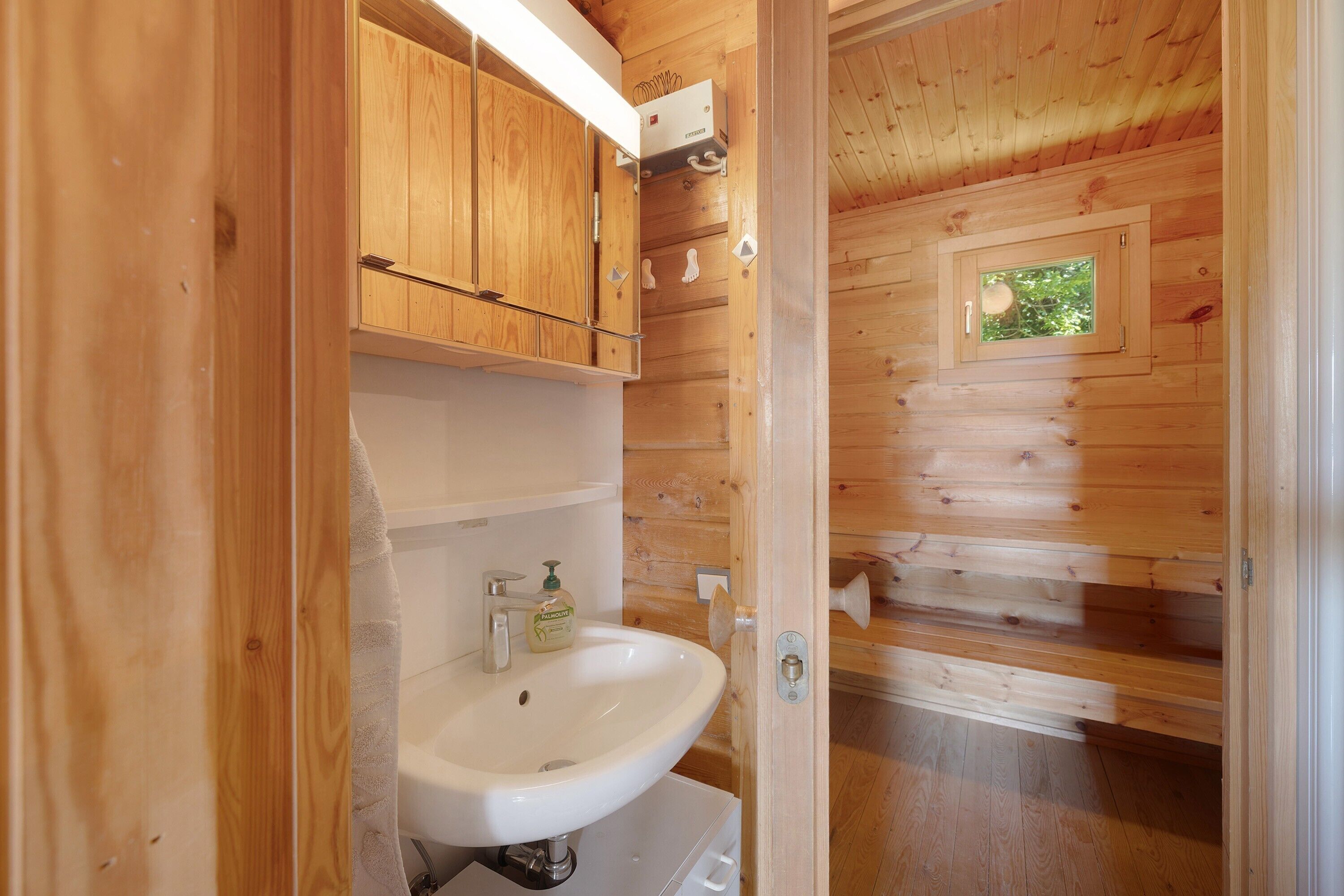 Une salle de bain rustique, située dans une cabane en bois, avec un lavabo, des placards et une fenêtre.
