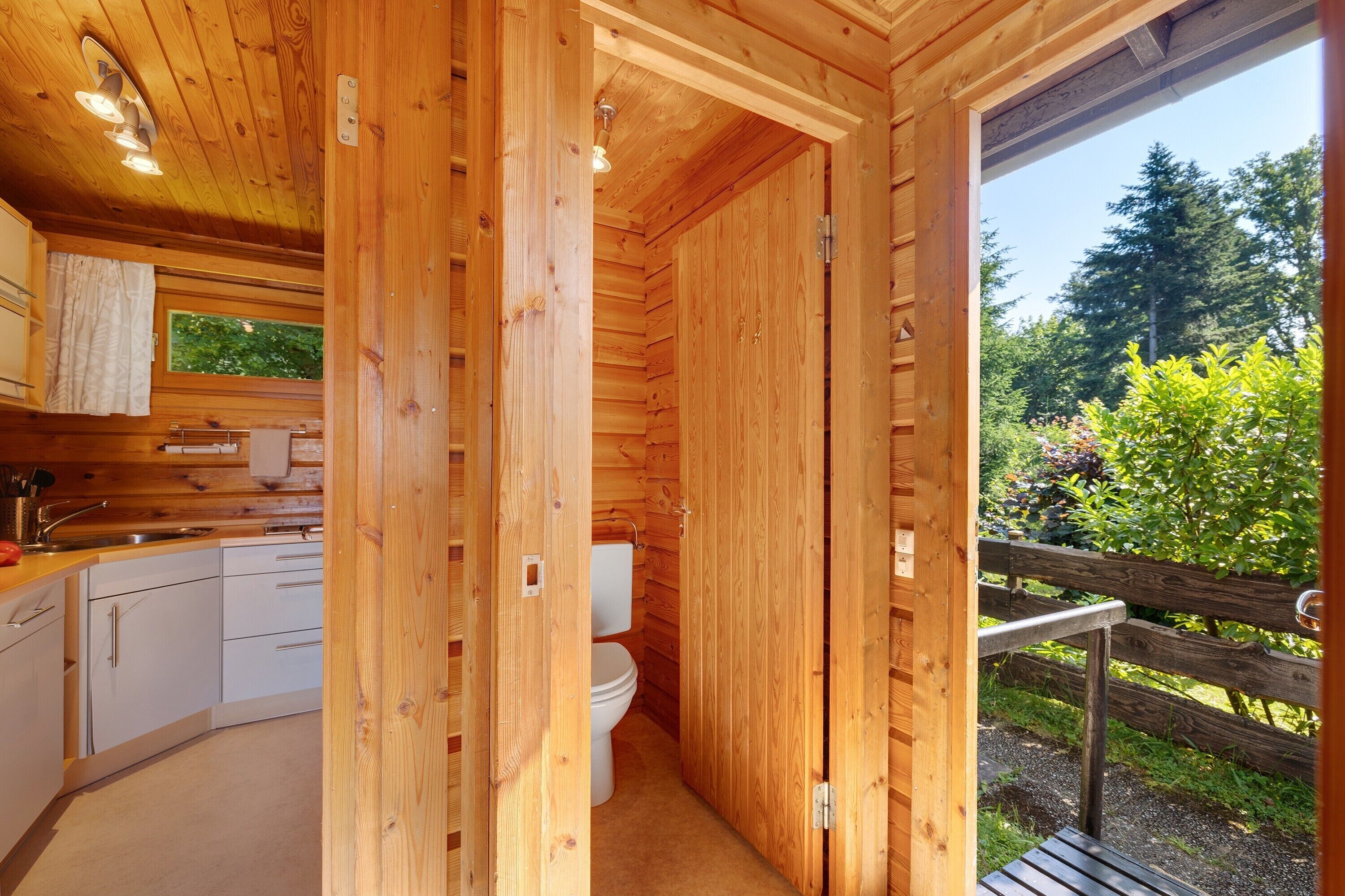 Une cabane en bois équipée d’une cuisine, de toilettes et offrant une vue sur l’extérieur.