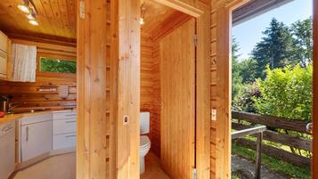 Une cabane en bois équipée d’une cuisine, de toilettes et offrant une vue sur l’extérieur.