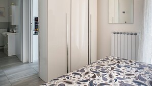 Et soveværelse med seng, garderobeskab, radiator og et spejl på væggen.