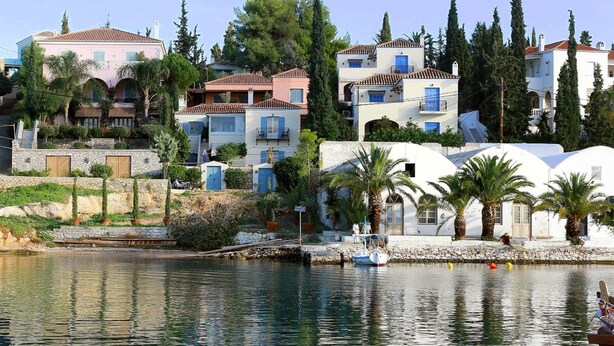 A coastal residential area with houses, a marina, and a clear sky.