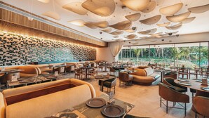 A modern restaurant with a unique ceiling design, large windows, and a patterned wall. - Clara Arte Resort (Brumadinho)