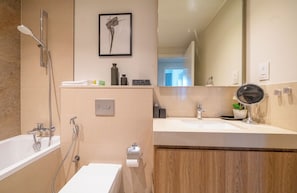 A modern bathroom with a bathtub, shower, and vanity with a mirror.