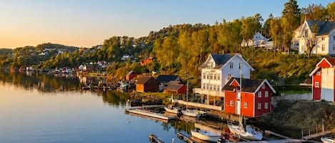 A calm waterfront with docked boats, a pier, and a cluster of houses with distinct architectural styles.