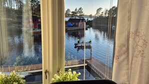 Une vue d’une rivière paisible, avec des bateaux et des maisons en arrière-plan.