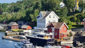 Une propriété située au bord de l’eau, avec une grande maison blanche, des bâtiments rouges et un quai où sont amarrés des bateaux.